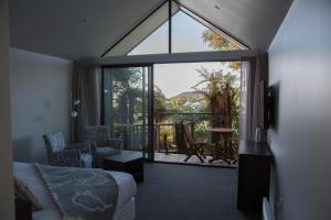 um quarto com uma cama e uma grande janela de vidro em Church Hill Boutique Lodge & Restaurant em Half-moon Bay