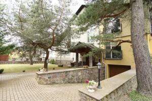 a house with a stone wall next to a tree at Birutės Vila in Palanga