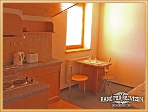 a kitchen with a counter and a table and a window at Ranc pod Rejvizem in Zlaté Hory