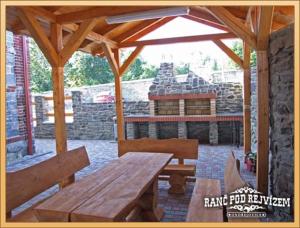 a wooden picnic table and benches in a pavilion at Ranc pod Rejvizem in Zlaté Hory