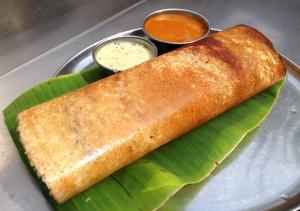 a plate of food with a roll on a banana leaf at Hills View Stay in Māvingundi