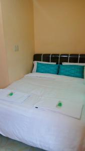 a white bed with blue and green pillows on it at Rome Residence Sibolga Pandan in Halangan