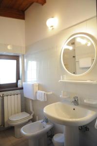 La salle de bains est pourvue d'un lavabo, de toilettes et d'un miroir. dans l'établissement Hotel Eternità, à Malonno