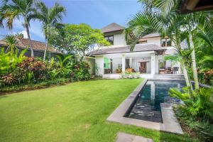 a villa with a swimming pool and a yard at Serene Villas in Seminyak