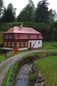ein Haus mit rotem Dach neben einem Fluss in der Unterkunft Chalupa U skály in Kytlice