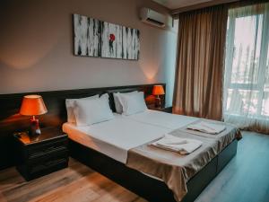 una camera da letto con un letto con lenzuola bianche e una finestra di Tskaltubo Hotel Prometheus a Tskhaltubo