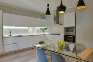 a kitchen with white cabinets and a glass table at Apartments Florence - Dello Sprone in Florence