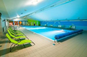 a large swimming pool with green chairs in a building at Drevenica Jánošík 2 in Terchová