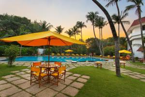a table and chairs with an umbrella next to a pool at Trident Chennai in Chennai