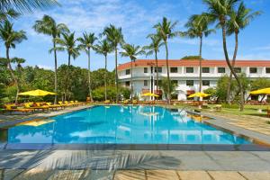 a swimming pool in front of a hotel with palm trees at Trident Chennai in Chennai