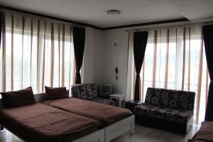 a bedroom with a bed and a chair and windows at Hotel Scorpion in Kru&scaron;evo