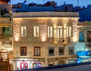 un vecchio edificio in pietra con luci accese di 1844 Suites Syros a Ermoupoli
