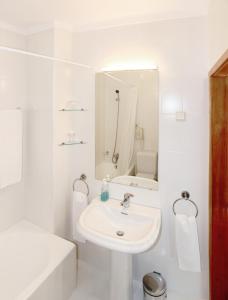 a white bathroom with a sink and a mirror at Hotel Caldelas in Caldelas