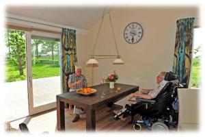 an older man in a wheelchair in a living room with a table at Fruitbedrijf Stek in Kedichem