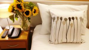 
a bed with pillows and a vase with flowers on it at The Pier Hotel in Limerick
