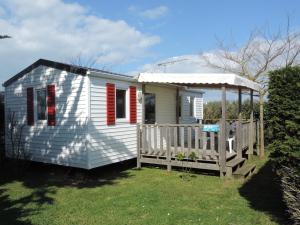 a small white house with red shutters and a porch at Camping Les Perouses in Saint-Clément-des-Baleines