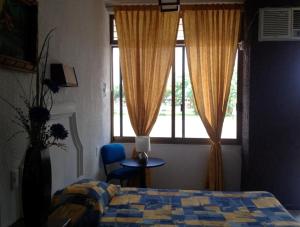 a bedroom with a bed and a window and a chair at Hotel Paraiso in Tepic