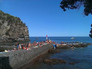 a group of people sitting on a wall at the beach at Caloura Camellia House in Caloura