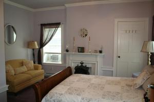 a bedroom with a bed and a chair and a fireplace at The 1819 Red Brick Inn in Dundee