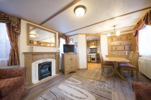 a living room with a fireplace and a table at Domek Promyk in Jurata