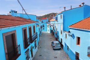 un coche aparcado en un callejón entre dos edificios azules en Casa Rural Fuente Caraila en Júzcar