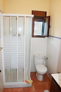 a bathroom with a toilet and a glass shower at Casa Rural Fuente Caraila in Júzcar