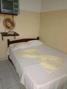 a bedroom with a white bed with a tv on the wall at Pousada Ipojuca in Caruaru