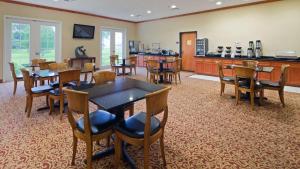 a dining room with tables and chairs and a kitchen at Best Western Inn & Suites Cleveland in Cleveland