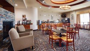 un restaurant avec des tables, des chaises et une cheminée dans l'établissement Best Western Plus Fort Worth Forest Hill Inn & Suites, à Fort Worth