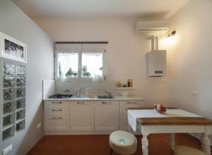 cocina con armarios blancos, mesa y ventana en Central Pitti Studio Flat, en Florencia