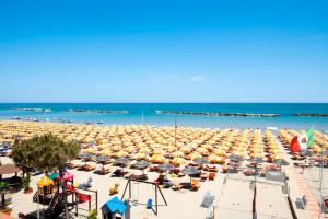 a beach filled with lots of chairs and umbrellas at Hotel La Conchiglia in Bellaria-Igea Marina