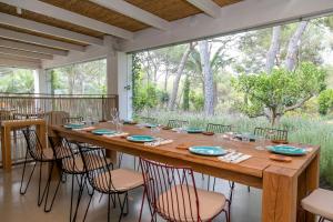 Casbah Formentera Hotel & Restaurant في بلايا ميجورن: طاولة خشبية كبيرة مع كراسي ونافذة كبيرة