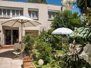 a patio with two umbrellas and chairs in front of a building at Villa Cemaste in Montpellier