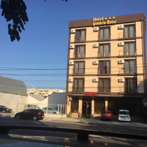 un edificio de hotel con coches aparcados en un aparcamiento en Golden Rose Residence en Constanza