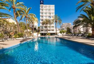 a swimming pool with palm trees and a tall building at Eurostars Marivent in Palma de Mallorca