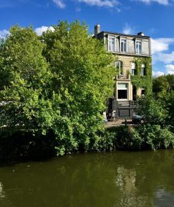 uma casa com árvores em frente a um corpo de água em Les Toquées Maison d'hôtes em Lille