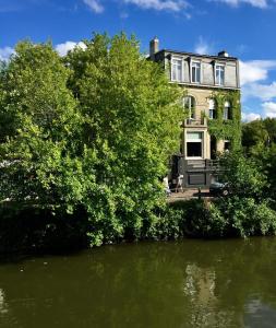 une maison avec des arbres devant une masse d'eau dans l'établissement Les Toquées Maison d'hôtes, à Lille