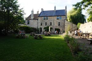 un antiguo edificio con mesas de picnic y gente en el patio en The Barge Inn en Bradford on Avon