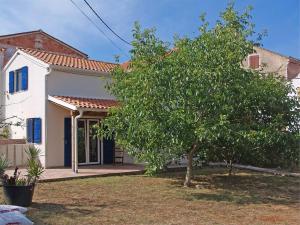 a small white house with a tree in the yard at Apartment Skiper in Veli Lošinj