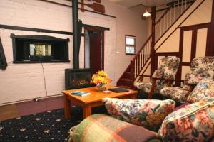 ein Wohnzimmer mit 2 Stühlen, einem Tisch und einem Kamin in der Unterkunft Westbury Gingerbread Cottages in Westbury