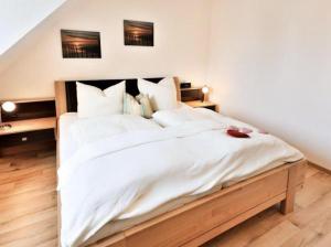 ein Schlafzimmer mit einem großen Bett mit weißer Bettwäsche und Kissen in der Unterkunft Appartement 34 - Ostseedomizil in Timmendorfer Strand