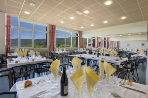 une salle à manger avec des tables et des chaises blanches avec des serviettes jaunes dans l'établissement L'ESCANDILLE Village Vacances, à Autrans