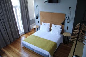 een slaapkamer met een groot bed met witte kussens bij Porto Music Guest House in Porto