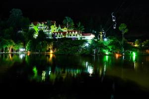 eine Gruppe von Häusern am Ufer eines Sees in der Nacht in der Unterkunft Hotel Fazenda China Park in Pedra Azul