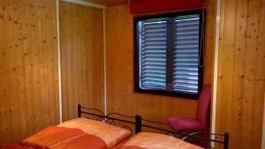 ein Schlafzimmer mit einem Bett, einem Fenster und einem Stuhl in der Unterkunft Ferienhaus Maxen in Müglitztal