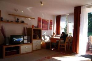 a woman sitting at a table in a living room at Falkenberg-Wohnung-201 in Oberstdorf