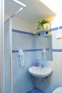 ローマにあるCasa Vacanza Frendy a Romaの青いタイル張りのバスルーム(シンク、鏡付)