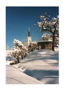 a snow covered church with a clock tower in the background at Sport-Alpin-Wohnung-9 in Oberstdorf