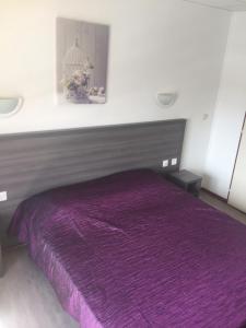 un letto con copriletto viola in una camera da letto di Hôtel Le Neptune a Soulac-sur-Mer