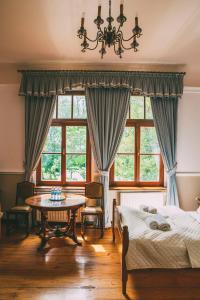 a bedroom with two beds and a table and windows at Pałac Poraj in Wicko
